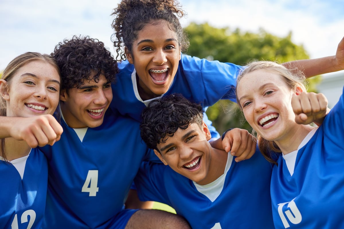 Smiling group of young teammates celebrating a joyful win of football match