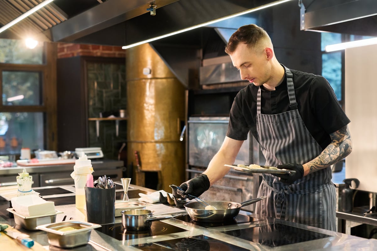 Ein junger Mann bereitet Essen in einer professionellen Küche vor