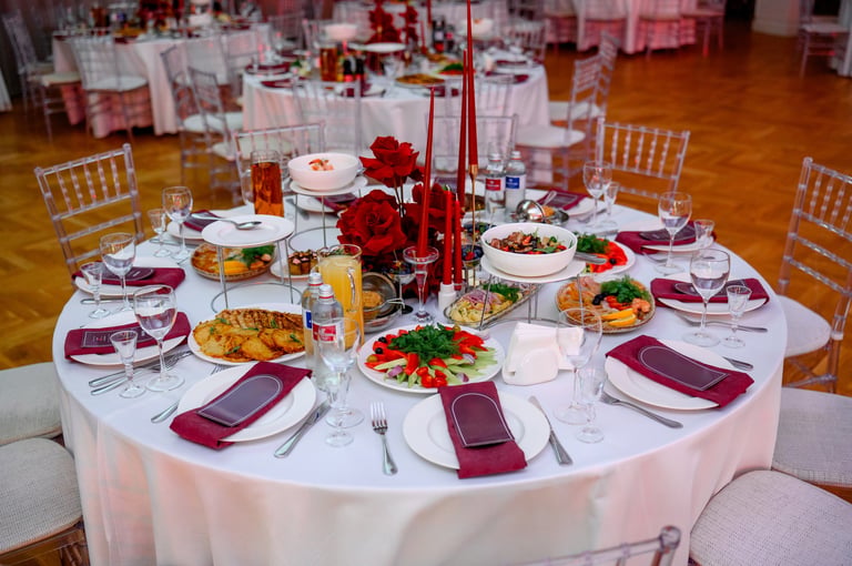 Rund gedeckter Esstisch mit Gourmetgerichten, Weingläsern und florale Gestecken