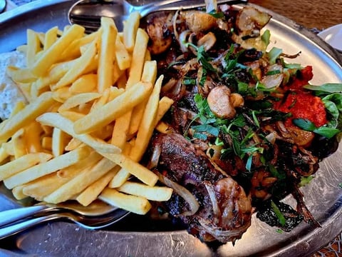 Gegrillte Fleischspieße mit Kräutern und Paprika, serviert mit knusprigen Pommes frites