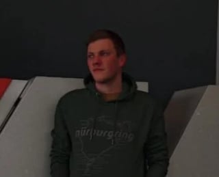 Man in dark hoodie sitting on couch against dark background