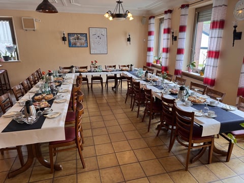Festsaal mit zwei langen Tischen für formale Anlässe, weiße Tischdecken und Holzstühle